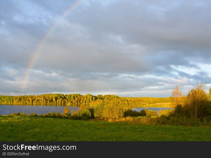 The cloudy sky and autumn rainbow above lake