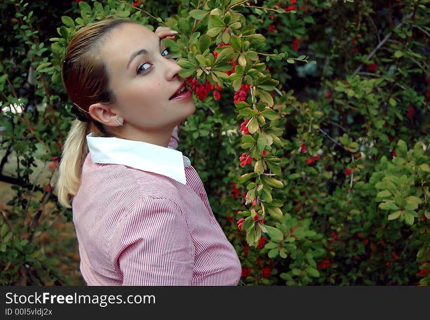 Coquetish girl trying to bite red barberries. Coquetish girl trying to bite red barberries