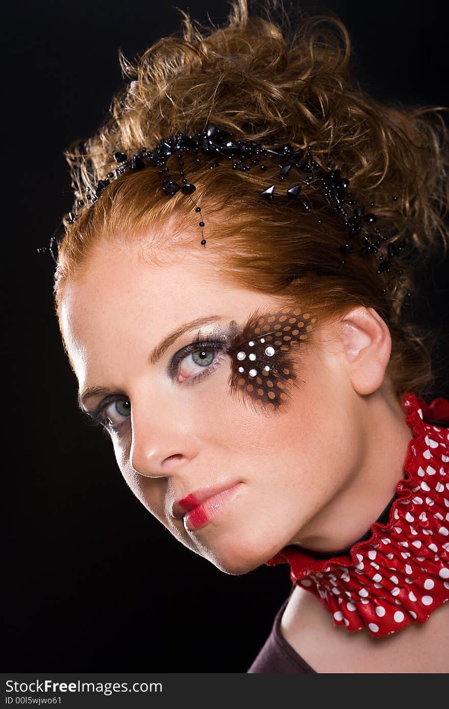 Attractive woman, unusual rogued, with feather on one eye and red-white vogue toby collar. Dark background. Attractive woman, unusual rogued, with feather on one eye and red-white vogue toby collar. Dark background.