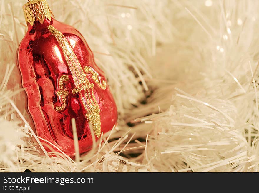 A piece of red and gold Christmas decoration shaped as a violin (cello, contrabass) in a cluster of white glittering strings. A piece of red and gold Christmas decoration shaped as a violin (cello, contrabass) in a cluster of white glittering strings.