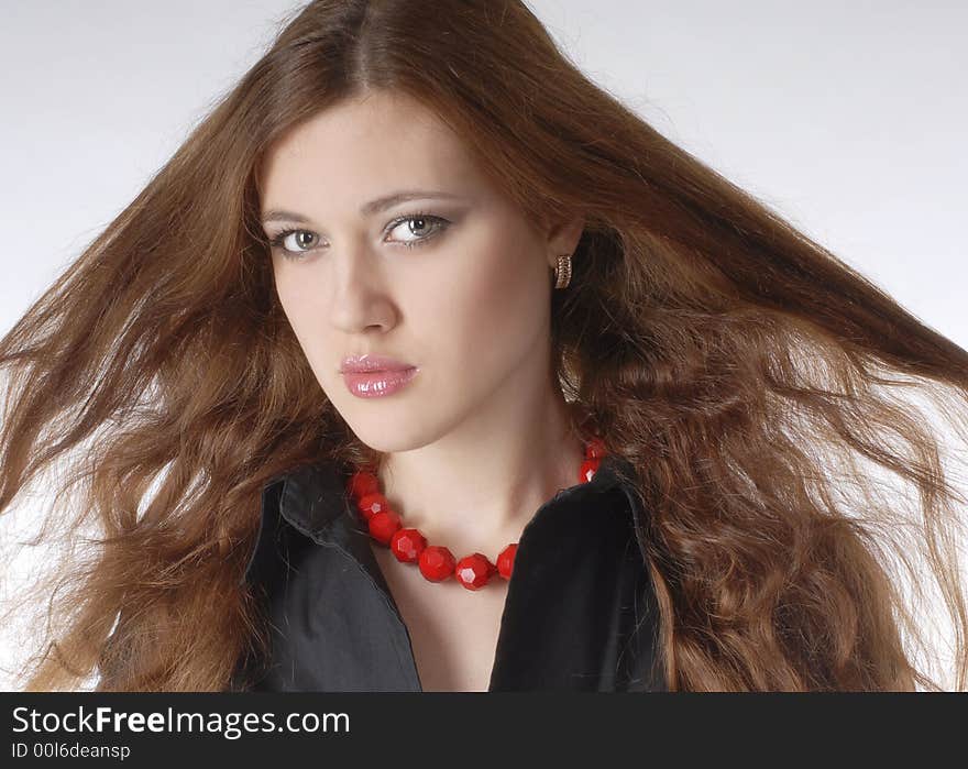 Girl in black dress and in red necklace on the white background close-up. Girl in black dress and in red necklace on the white background close-up