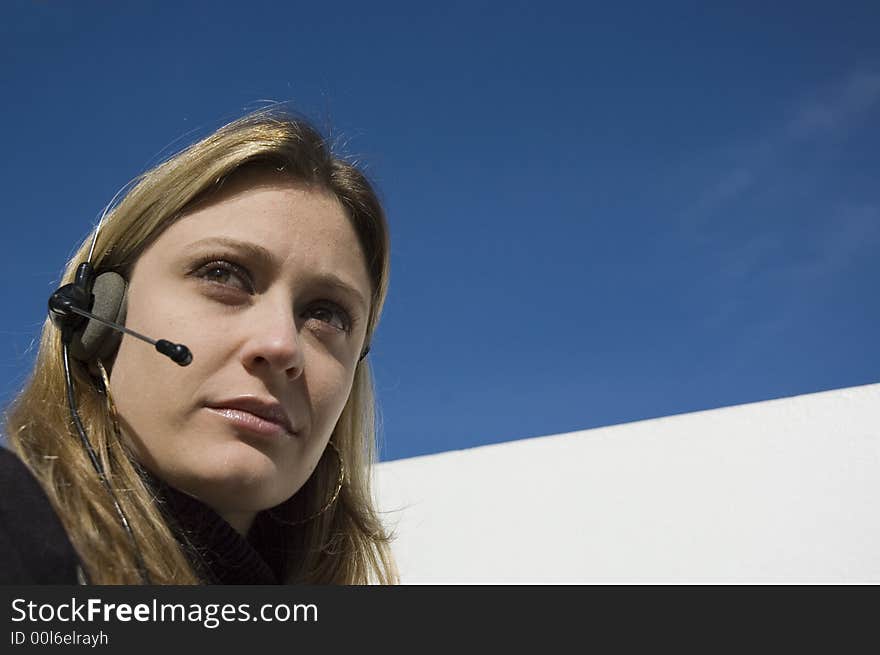 An isolated picture of a young female telemarketer / customer support officer, smiling as she works with a headset and microphone on her head. An isolated picture of a young female telemarketer / customer support officer, smiling as she works with a headset and microphone on her head.