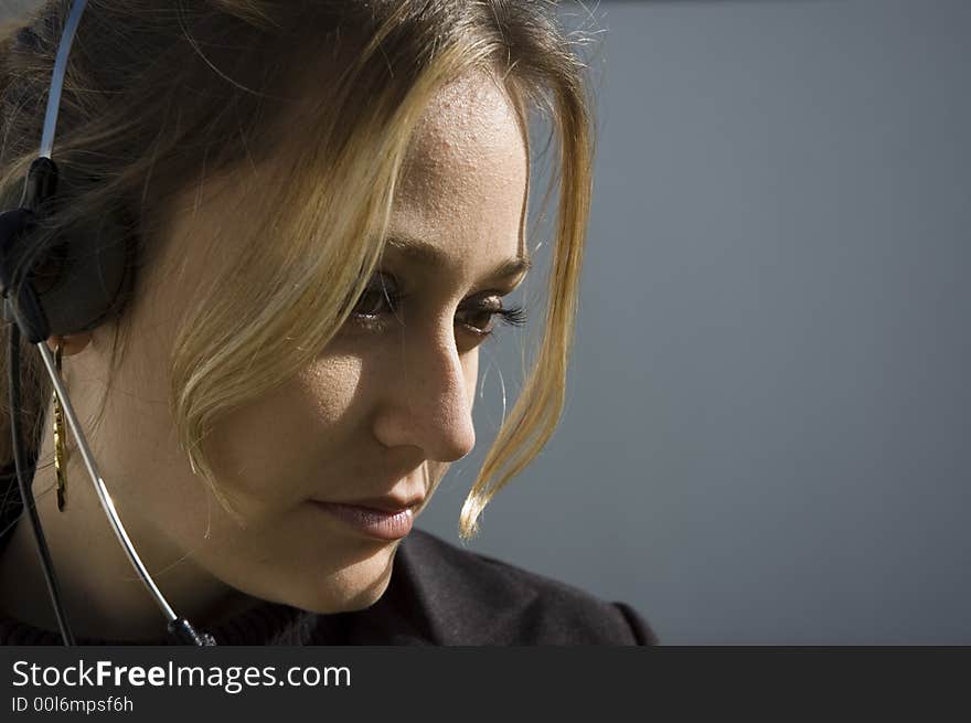 An isolated picture of a young female telemarketer / customer support officer, she works with a headset and microphone on her head.