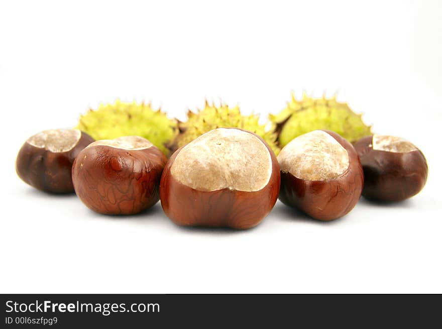 Chestnuts with shells behind. Isolated on white.