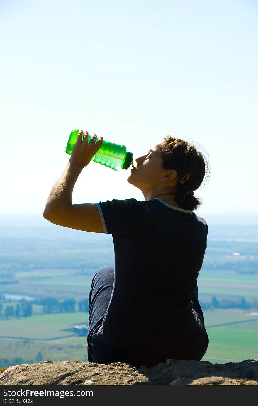 Drinking woman on top of a mountain