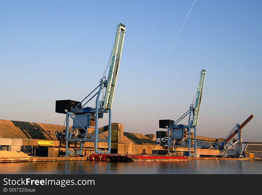 Two similar blue harbor cranes waiting for the next shipload