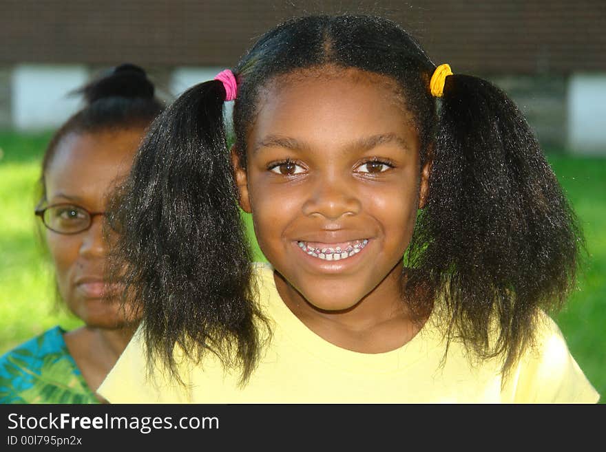 A picture of a little girl smiling with woman in the background. A picture of a little girl smiling with woman in the background