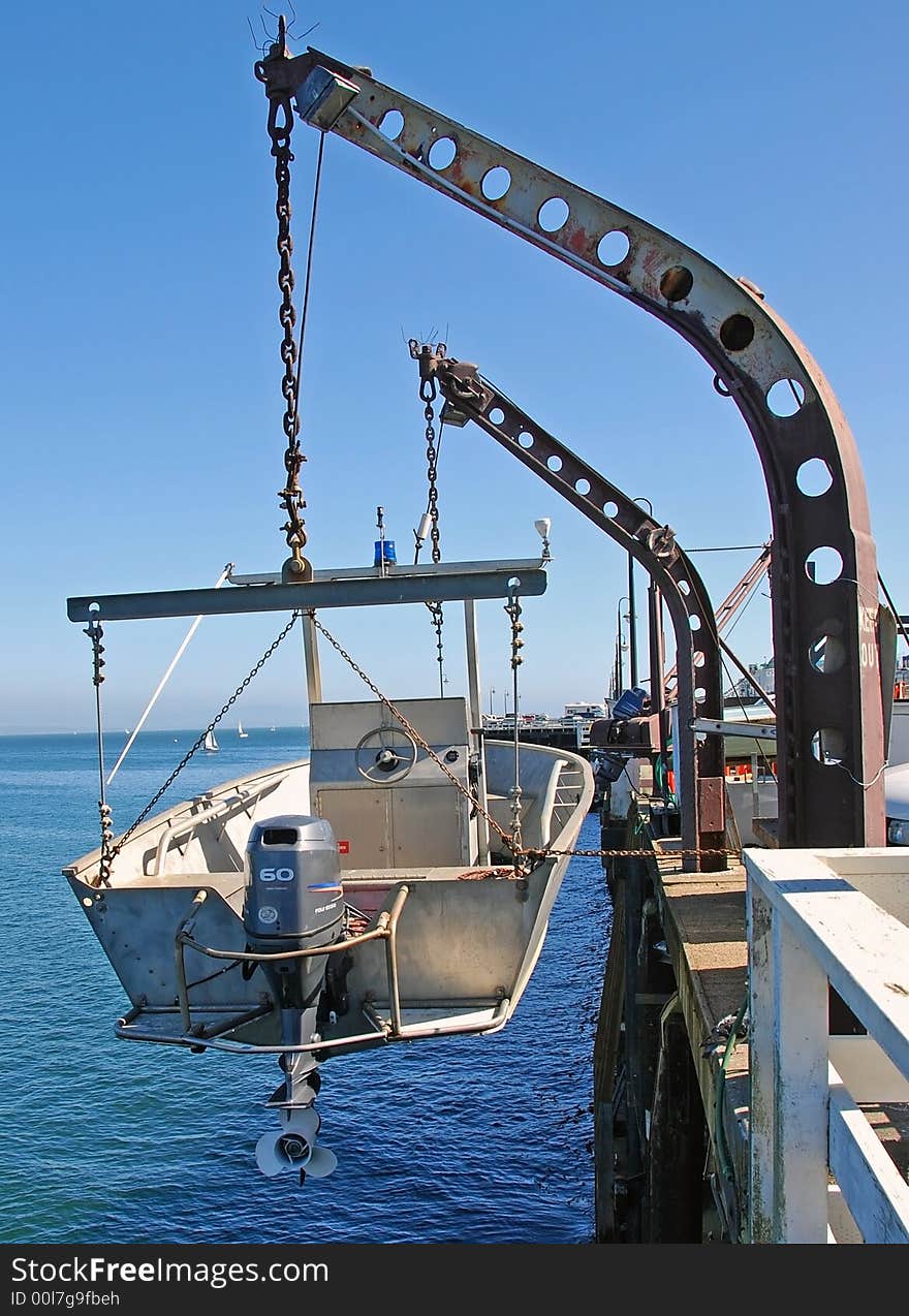 Small fishing troller hanging from davits on a fishing pier. Small fishing troller hanging from davits on a fishing pier