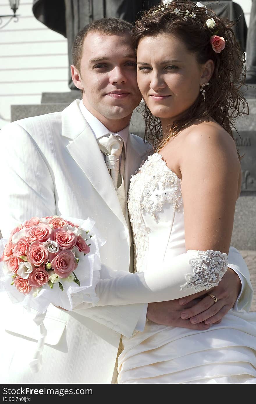 Just married - young couple in wedding wear with bouquet of roses