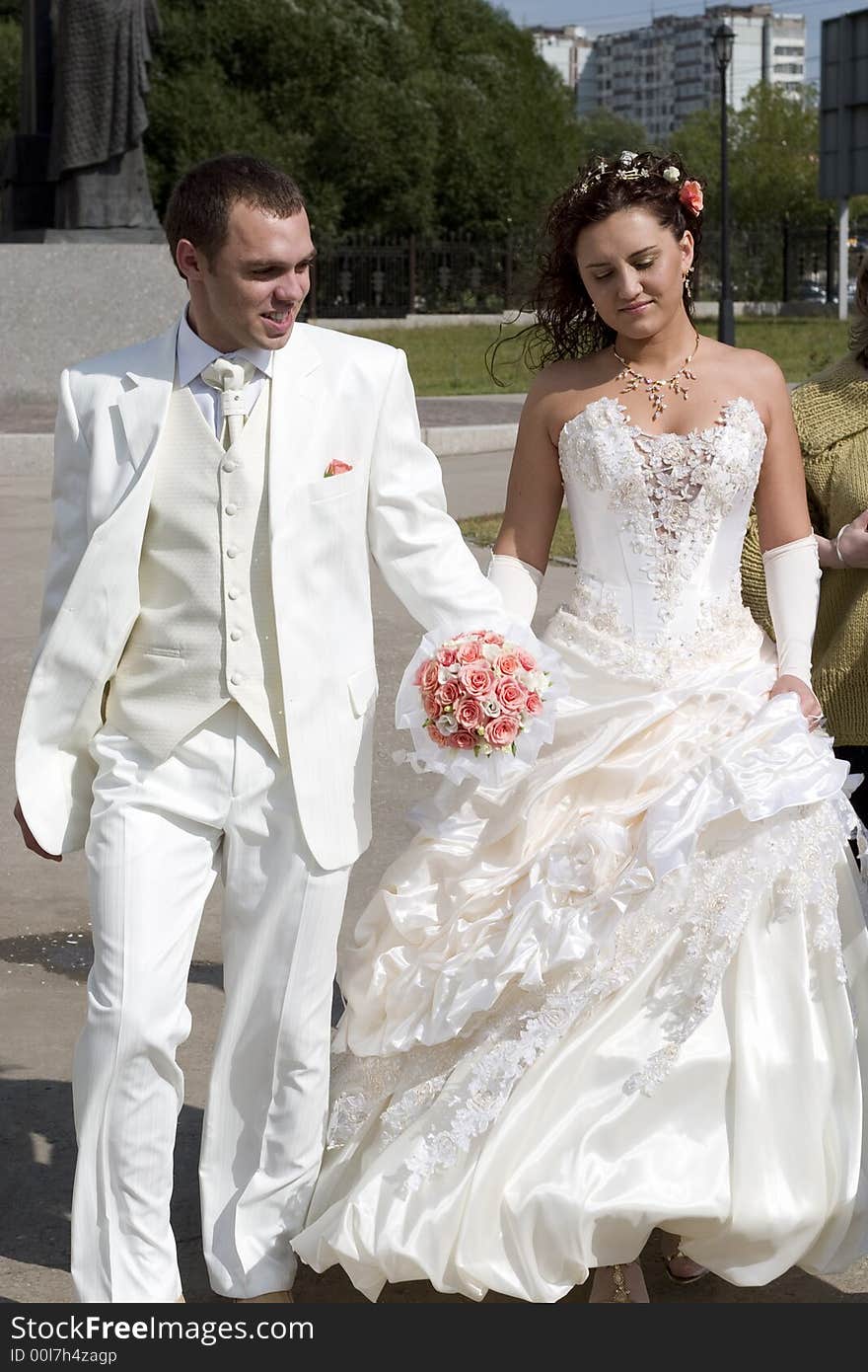 Just married - young couple in wedding wear with bouquet of roses