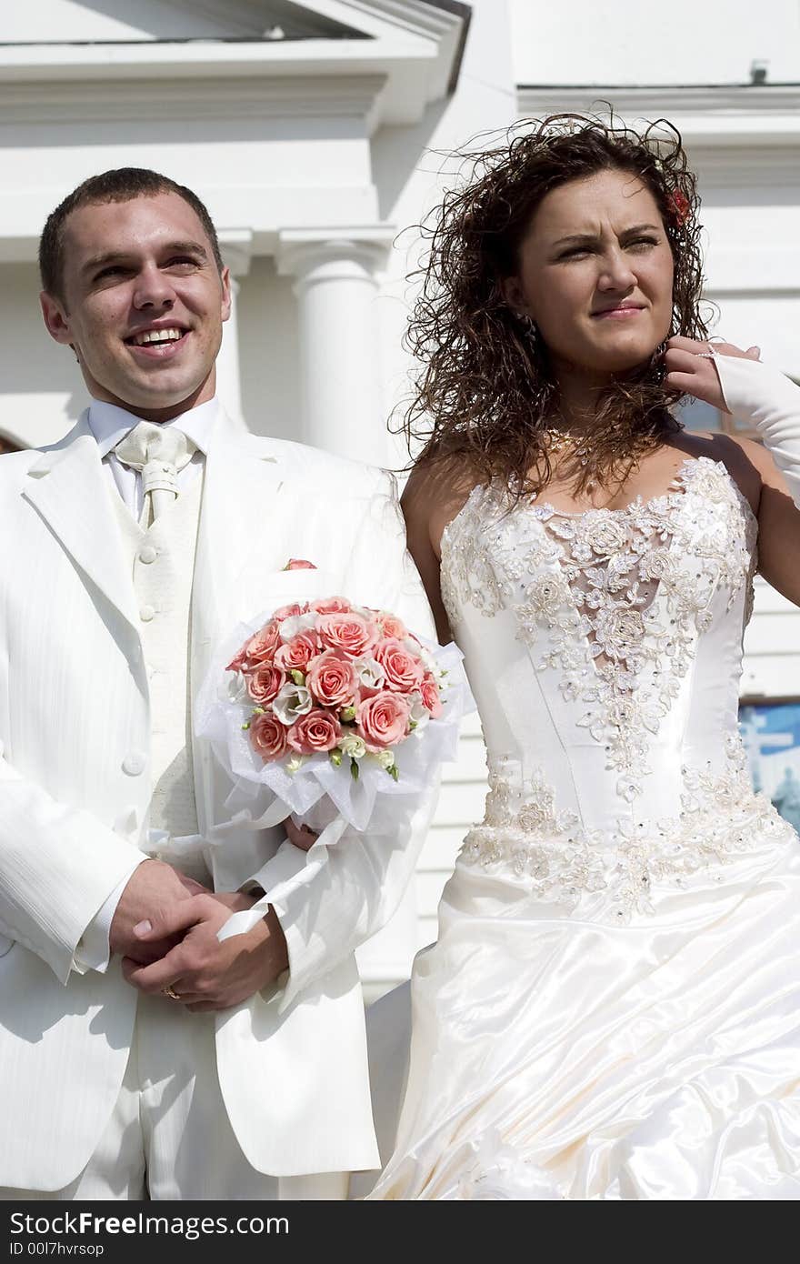 Just married - young couple in wedding wear with bouquet of roses