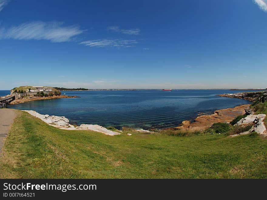 Taken at La perouse, Sydney, NSW, Australia on a clear day with blue sky white cloud, blue beach, rocky bay, green grass, big red boat from a distance. Landscape, bay view. Taken at La perouse, Sydney, NSW, Australia on a clear day with blue sky white cloud, blue beach, rocky bay, green grass, big red boat from a distance. Landscape, bay view.