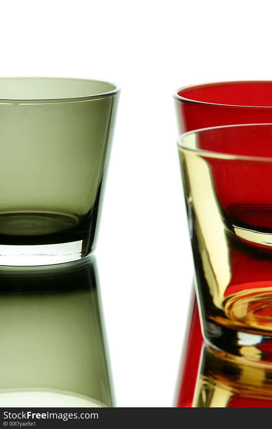 Colorful empty glasses over a white reflective background