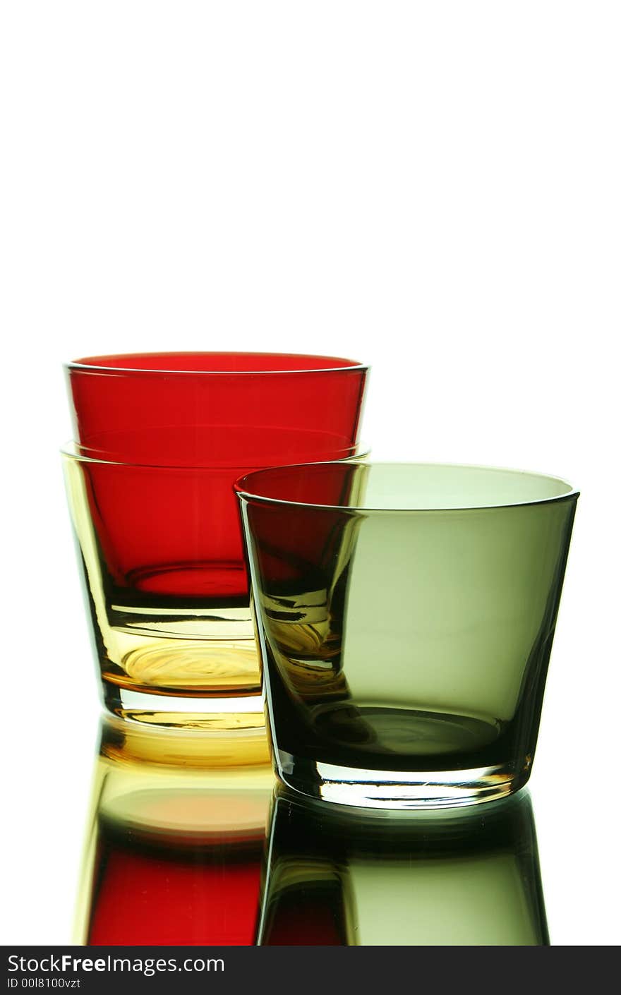 Colorful empty glasses over a white reflective background