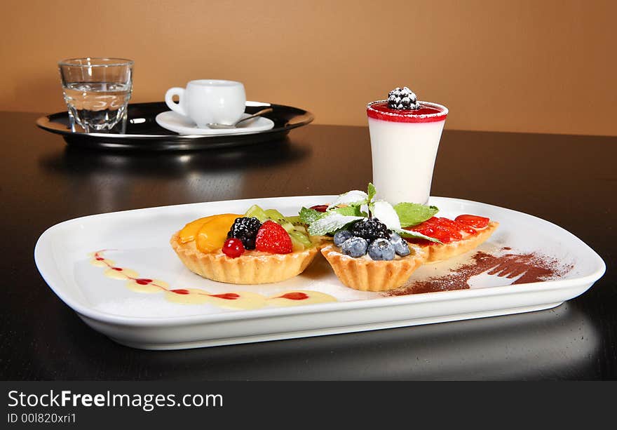 Mixed desert plate with panacotta and summer berries accompanied by coffee tray