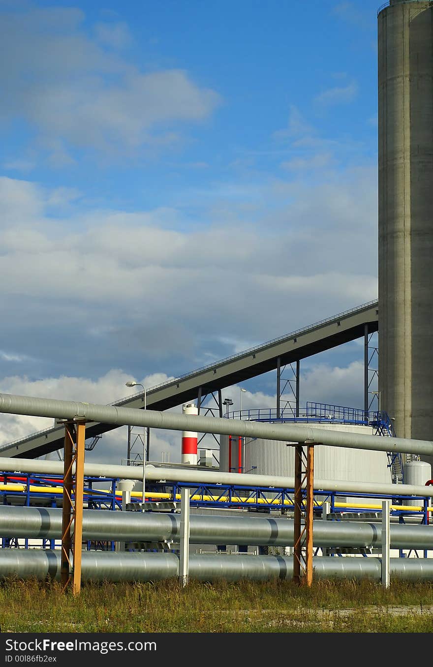 Pipe-bridges and silos in harbor against blue sky