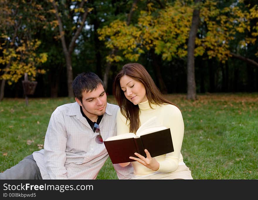 Young couple reading a book at the park. Young couple reading a book at the park