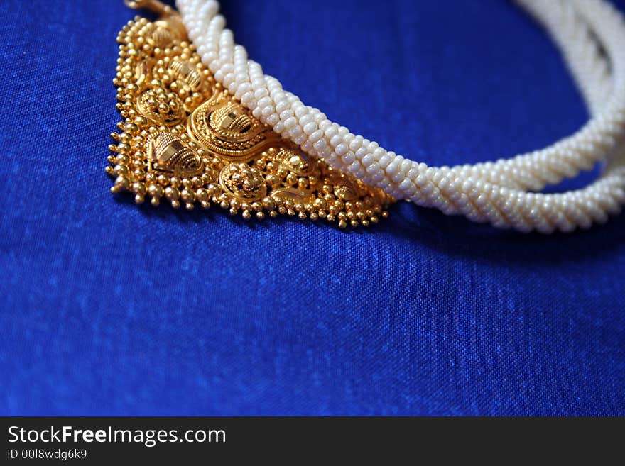 Gold and pearl jewelery necklace on blue background. Gold and pearl jewelery necklace on blue background.