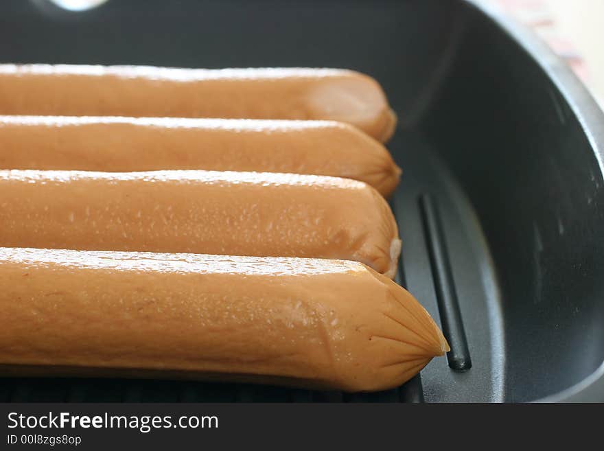 Four frozen but thawing jumbo frankfurters for pan frying