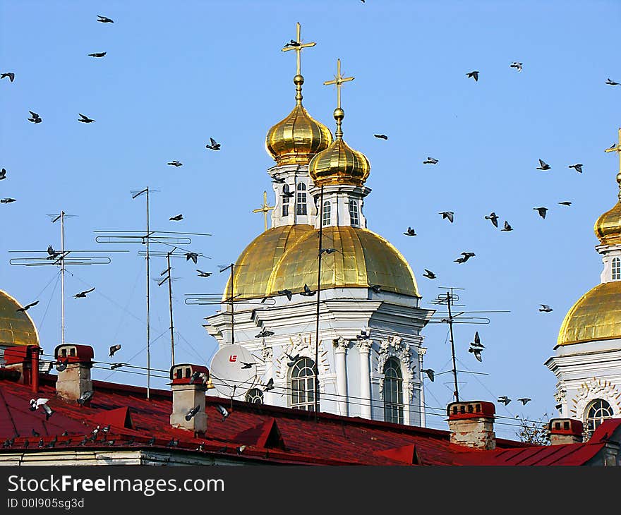 Gold domes of an orthodox cathedral in St.-Petersburg in Russia. Above domes and crosses pigeons fly to warm clear day. Gold domes of an orthodox cathedral in St.-Petersburg in Russia. Above domes and crosses pigeons fly to warm clear day.