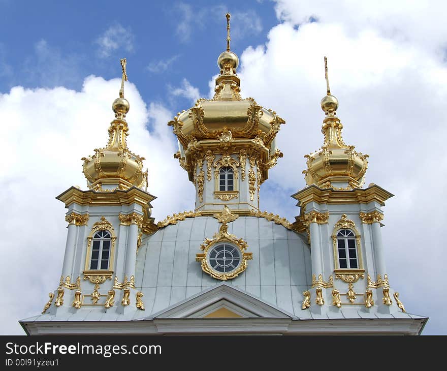 Three gold domes against the background blue sky with clouds.