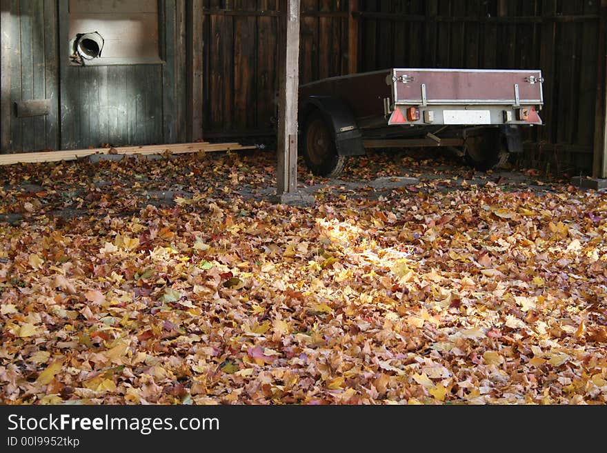 A car trailer parked in a garage surrounded by autumn leaves. A car trailer parked in a garage surrounded by autumn leaves