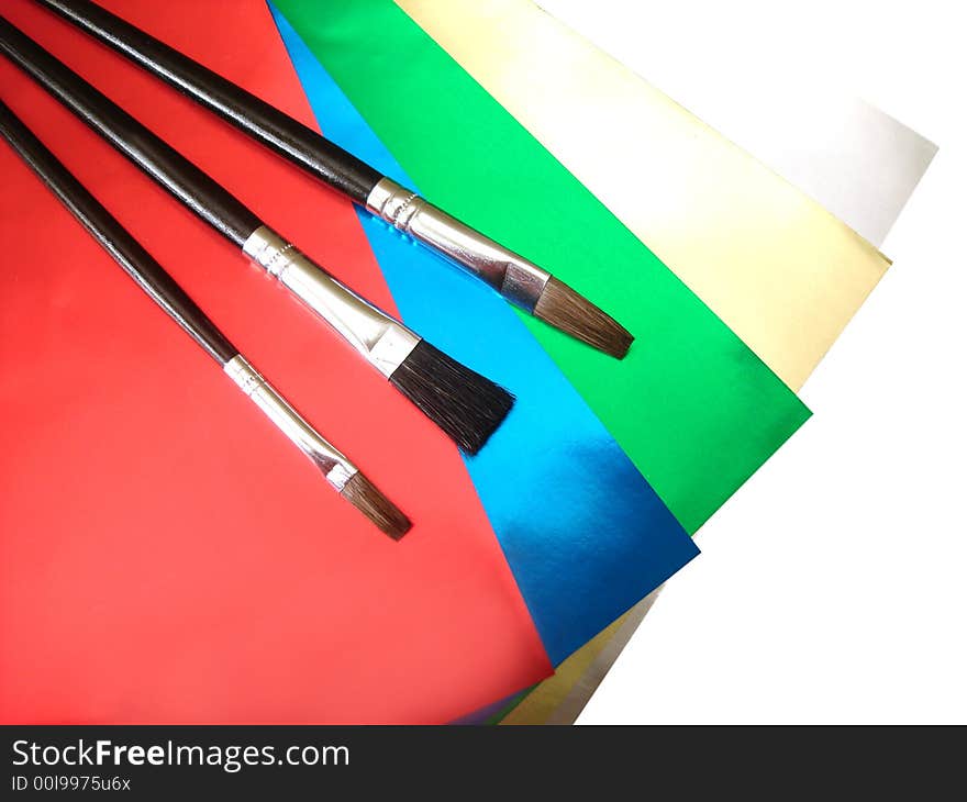 Three paint brushes on colored papers