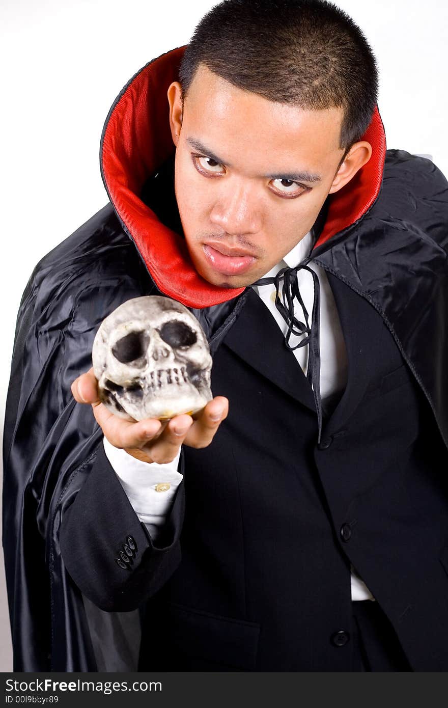 Scary man in cape holding dead skull on his hand.