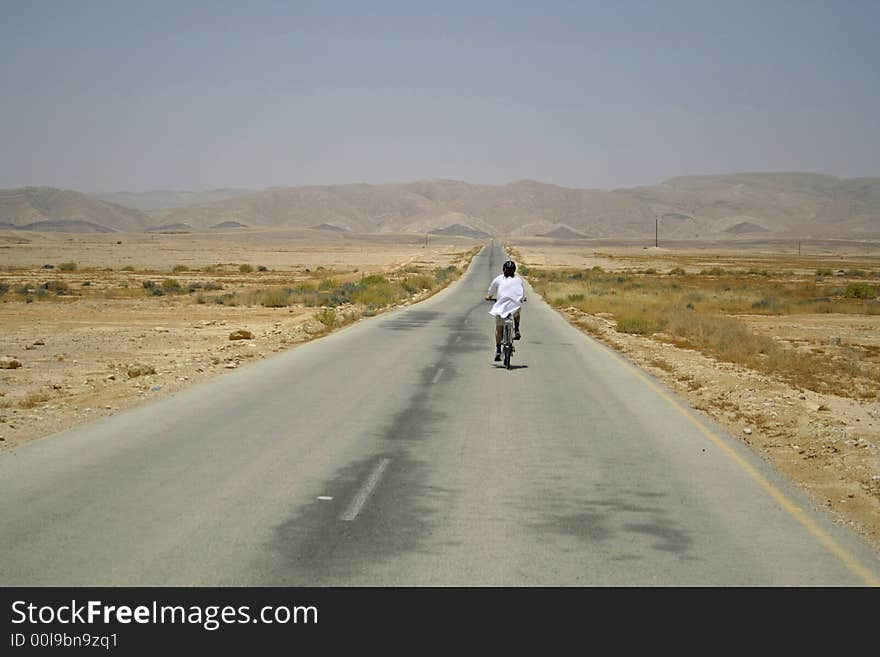 Man cycling on desert road