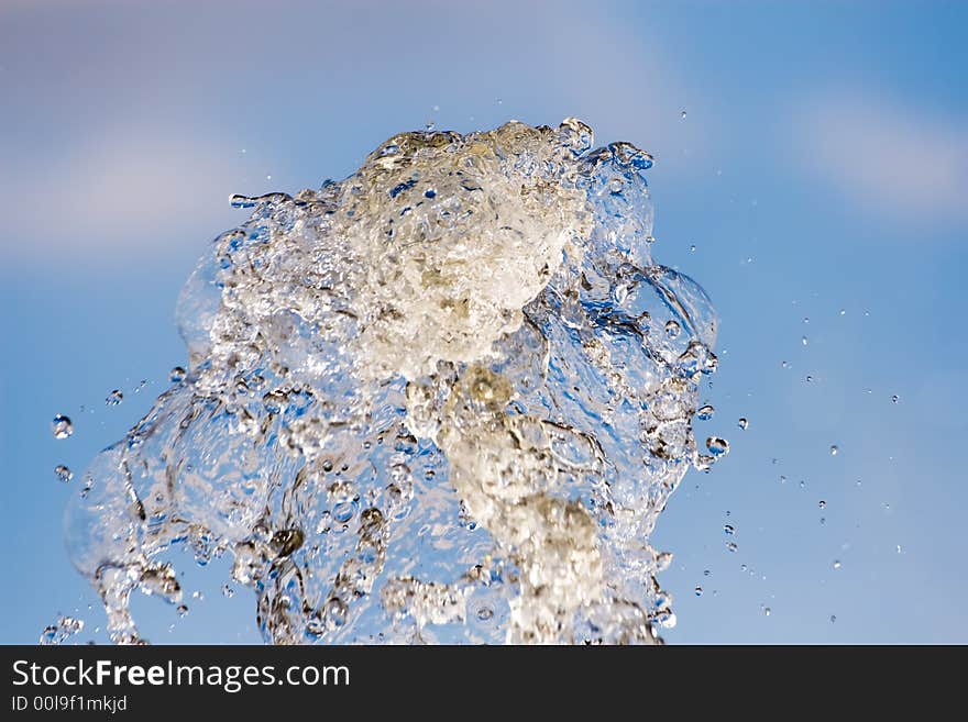 Splash of water on a background of the blue sky with clouds