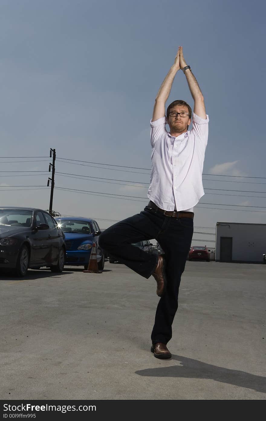 Young working man with beard performs a Yoga stretch on the top a parking lot. Young working man with beard performs a Yoga stretch on the top a parking lot.