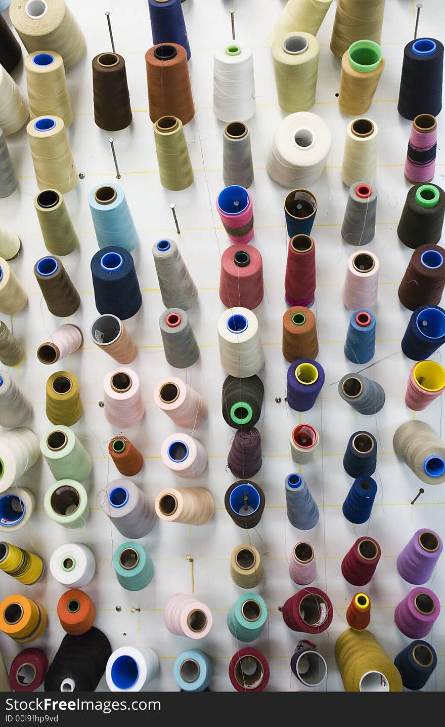 Wall board with multi colored thread spools inside a textile shop. Wall board with multi colored thread spools inside a textile shop.