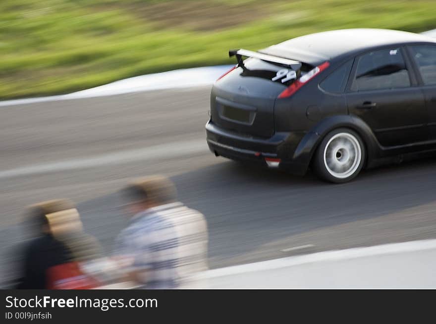 Black sport car moving at high speed along stand