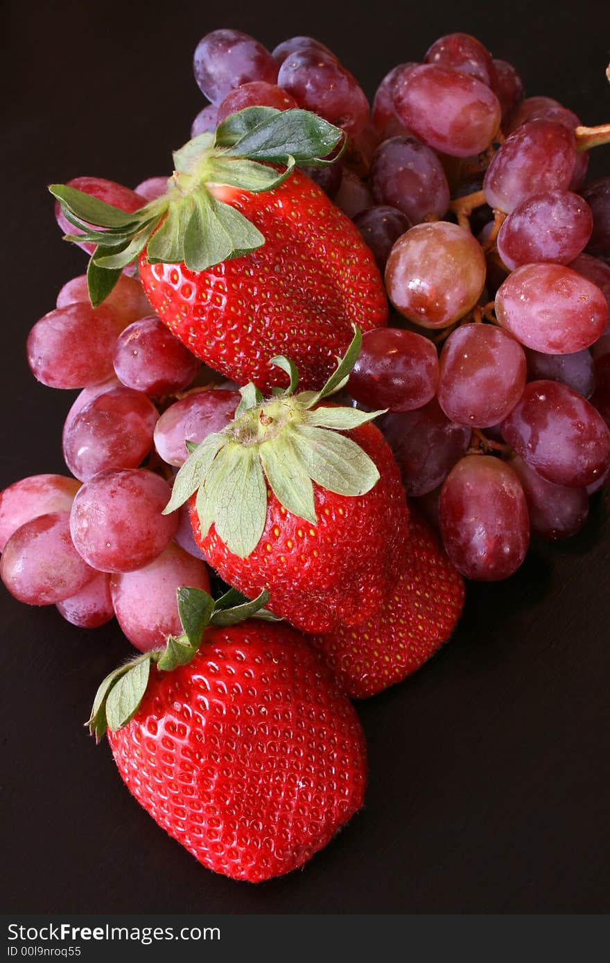 Healthy strawberries and red grapes on a dark surface. Healthy strawberries and red grapes on a dark surface