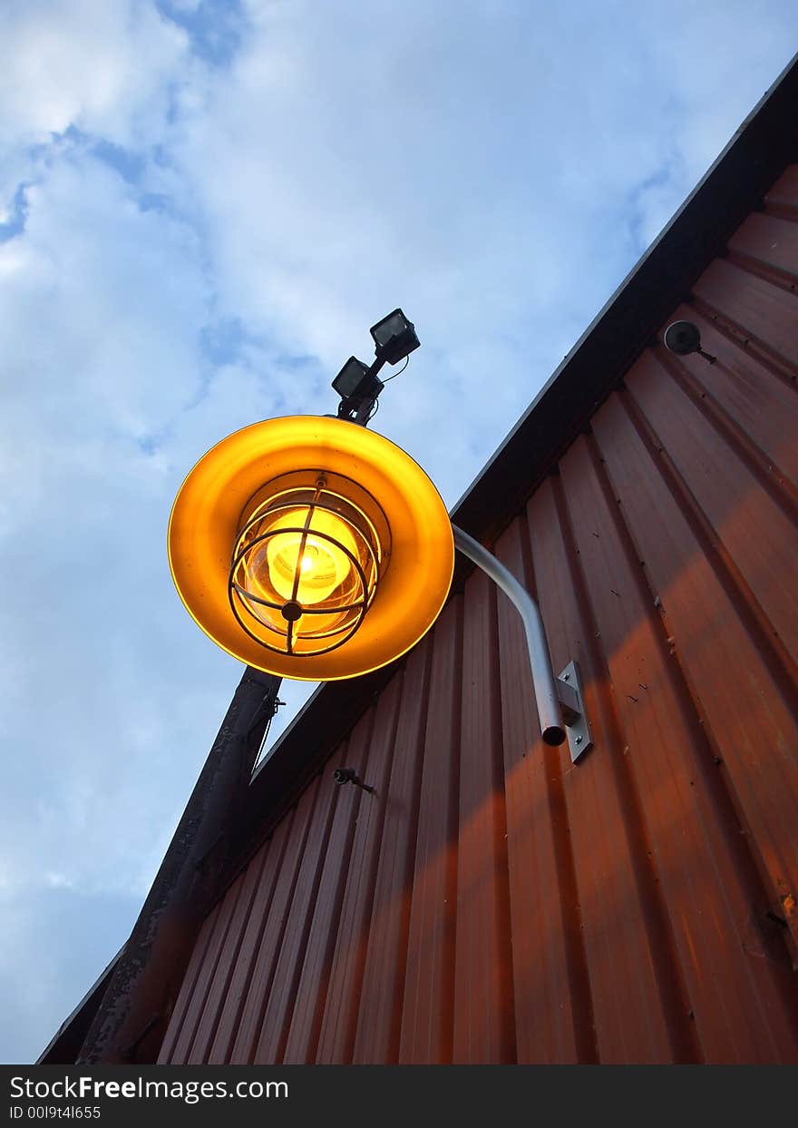 A bright yellow lamp on the side of a building. A bright yellow lamp on the side of a building.