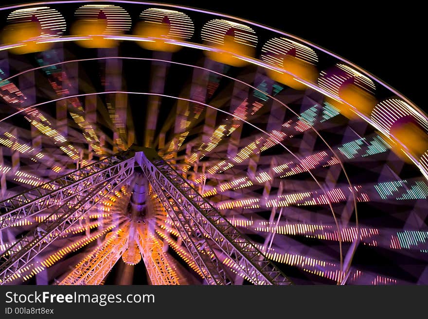 Illuminated ferris wheel at funfair. A night scene. Illuminated ferris wheel at funfair. A night scene.