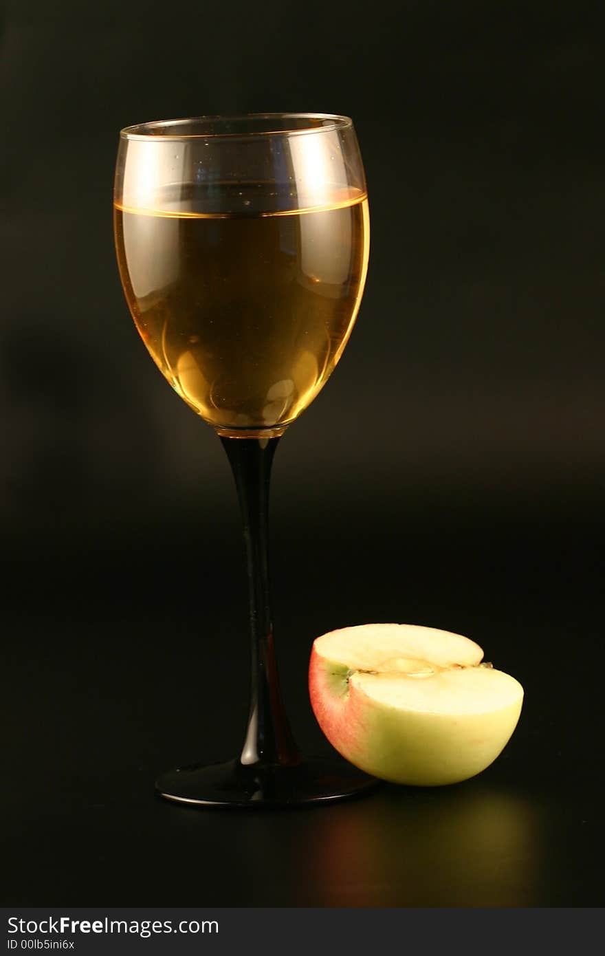 Glass of white wine and an apple on a black background. Glass of white wine and an apple on a black background