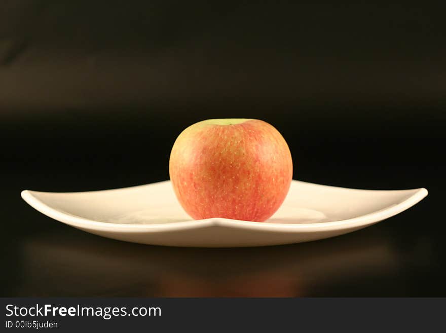 Plate with an apple on a black background