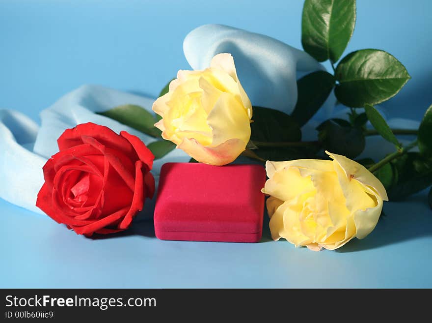 Roses and a box with a gold ring on a blue background.