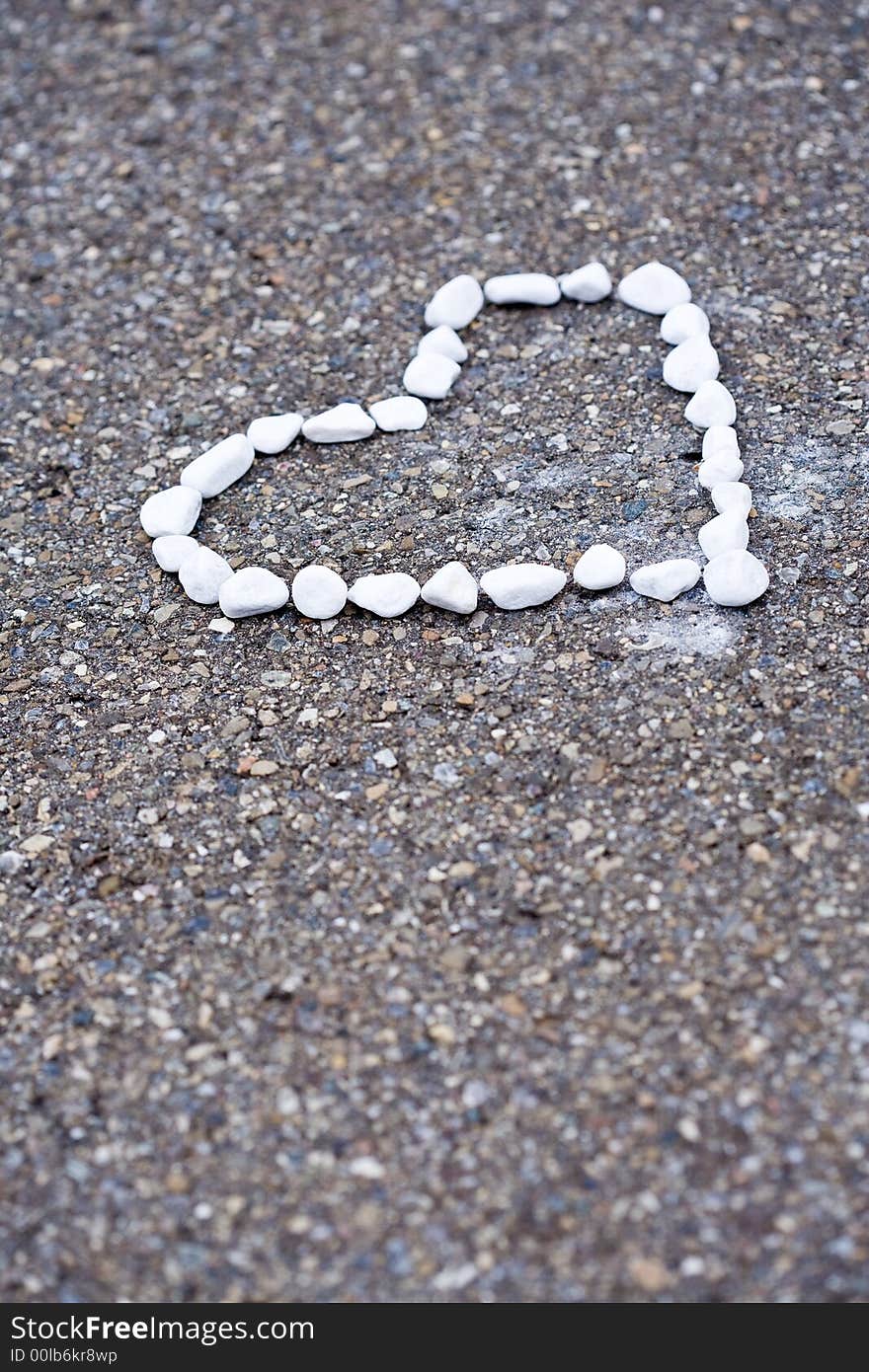 White stones on asphalt. Heartshaped.