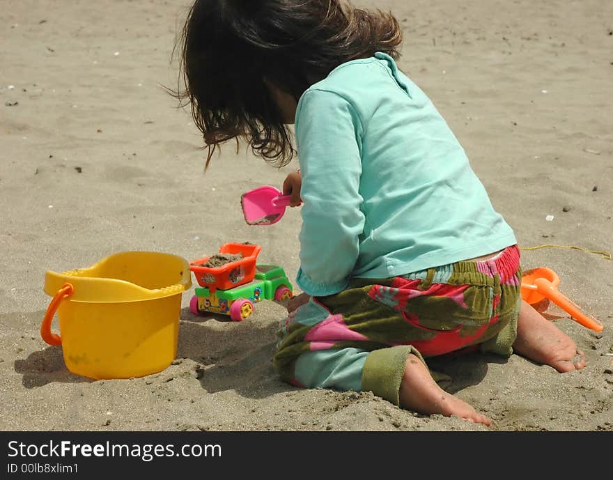 Little girl, sand and toys