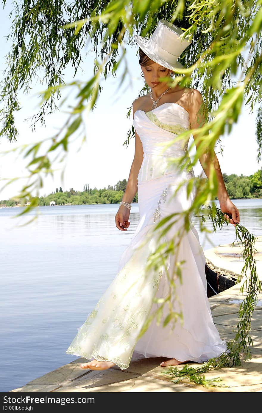 A bride standing between tree branches in her dress. A bride standing between tree branches in her dress