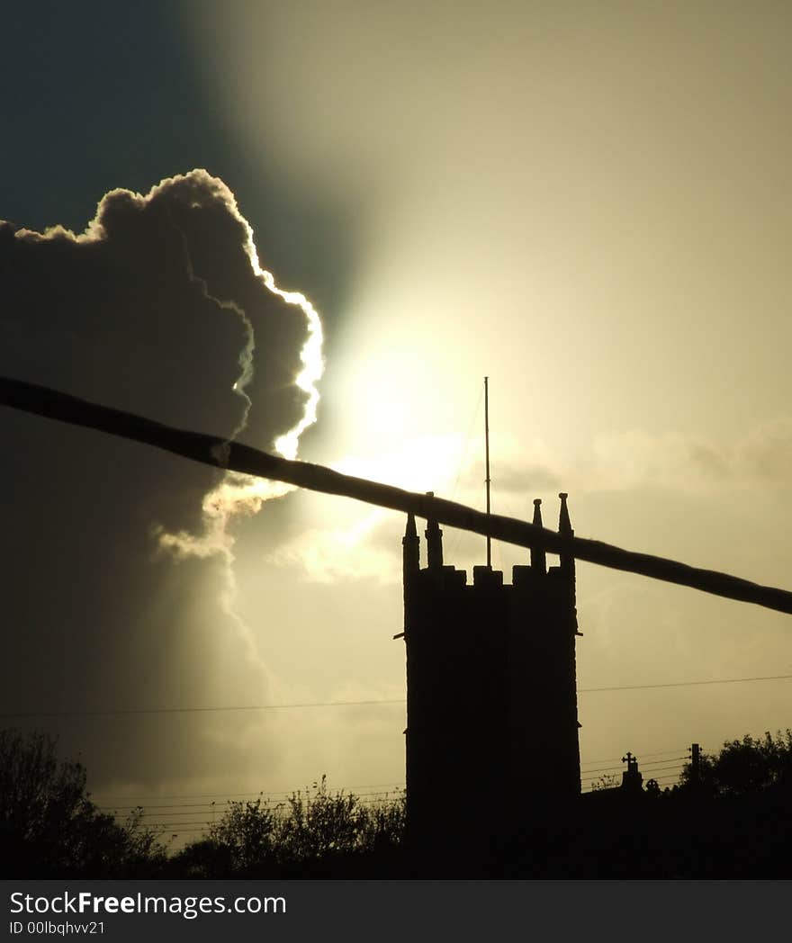 Church silhoutted by sun & dark clouds