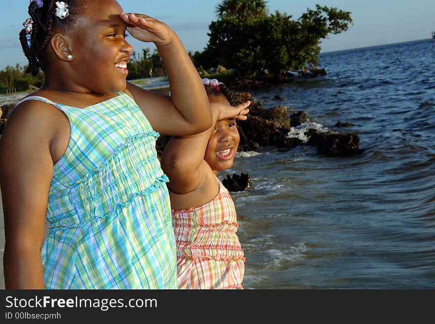 Two tween girls at a rocky coastline, looking at the sea. Two tween girls at a rocky coastline, looking at the sea.