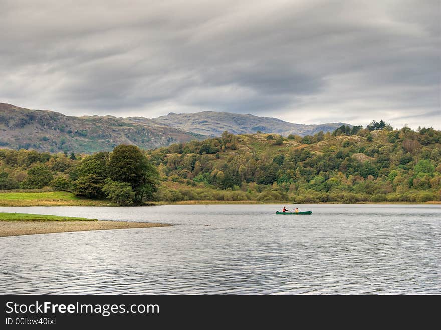 Two people canoeing on Rydal Water in the English Lake District under an overcast sky. Two people canoeing on Rydal Water in the English Lake District under an overcast sky