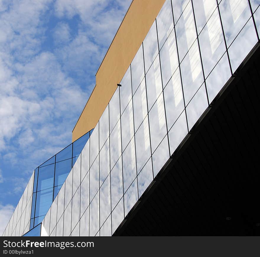 Modern building with glass windows and a modern design agains a cloudy  sky