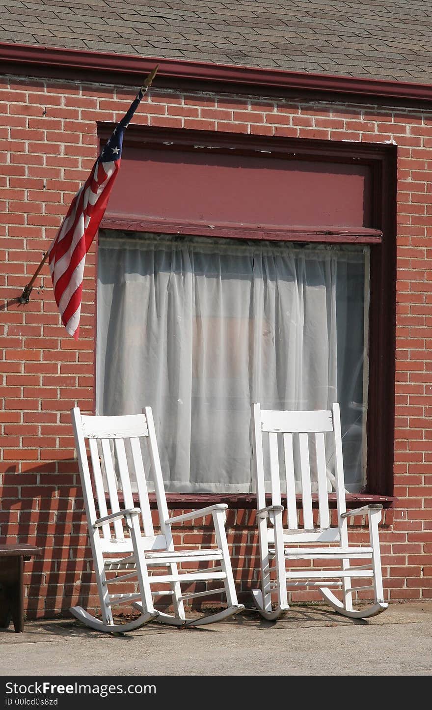 White rocking chairs on the sidewalk of a public street. White rocking chairs on the sidewalk of a public street