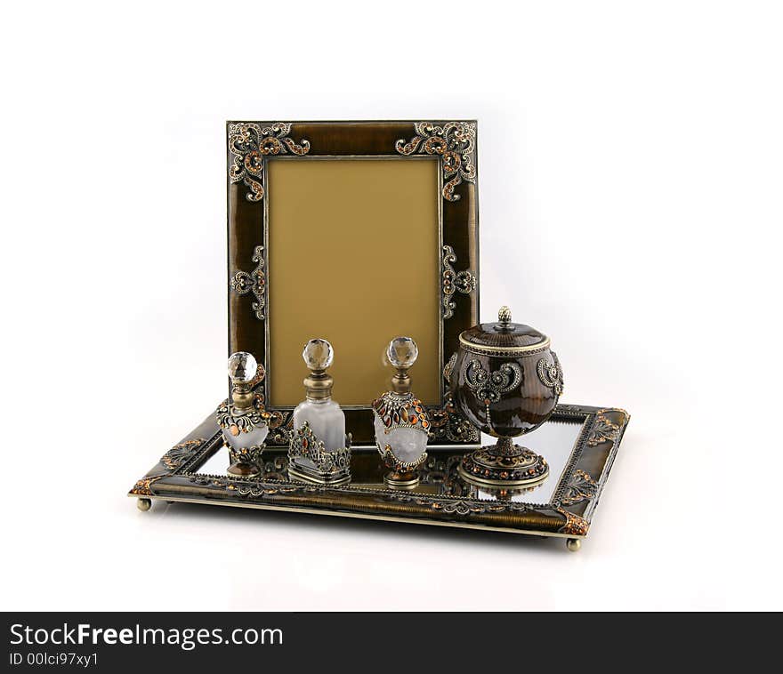 Picture frame, jewelry case and perfume bottles on mirrored tray. Picture frame, jewelry case and perfume bottles on mirrored tray