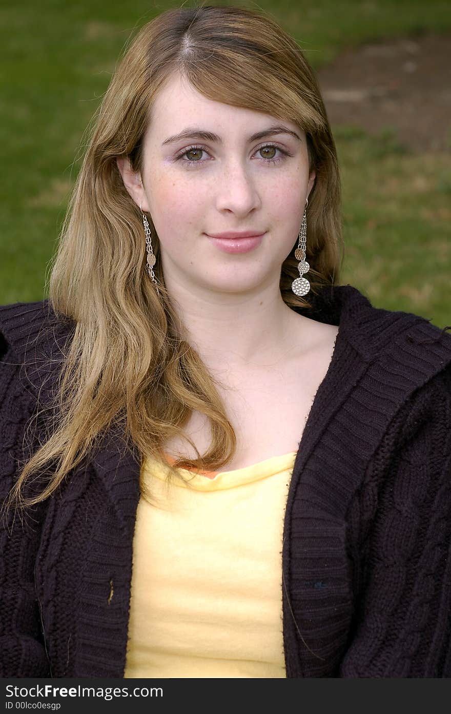 Young beautiful teen outdoors at the park with a different view, pose, and black sweater. Has a fall or winter season look.