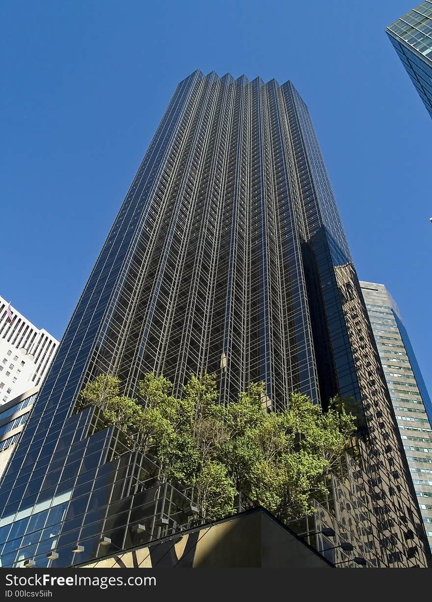 A modern tall building in Manhattan with trees planted on the lower levels. A modern tall building in Manhattan with trees planted on the lower levels.